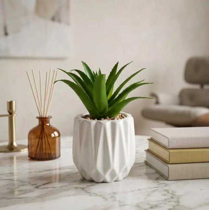 أصيص سيراميك أبيض بتصميم هندسي بارز مع نبتة صناعية
